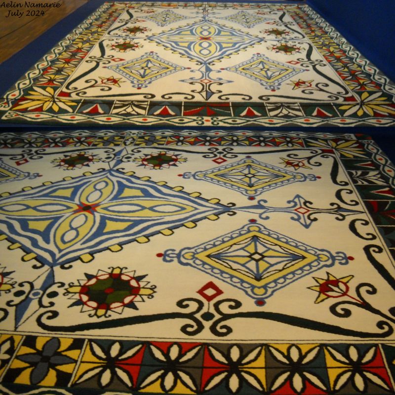 Numenorean carpet
Tolkien never drawed the Numenor island itself. In place, he imagined a lot of things being done by its inhabitants at the top of their glory.
The carpet was done differently than the tapestries, in "haute-lisse" (meaning a vertically loom). The tapestries are done in "basse-lisse" (almost horizontally loom).
Such a carpet was done with "point noué", a technique still used nowadays.
It's soft under the eyes. I had to remove a dust from it one day, believe me, like for the tapestries it's rigid. And its weight? I don't know exactly. But what I can tell is a tapestry makes between 1 and 2 kilos by m². For a carpet it's around 3 kilos by m².
Like for any piece of the hanging wall, the carpet shows the signature of Tolkien.

